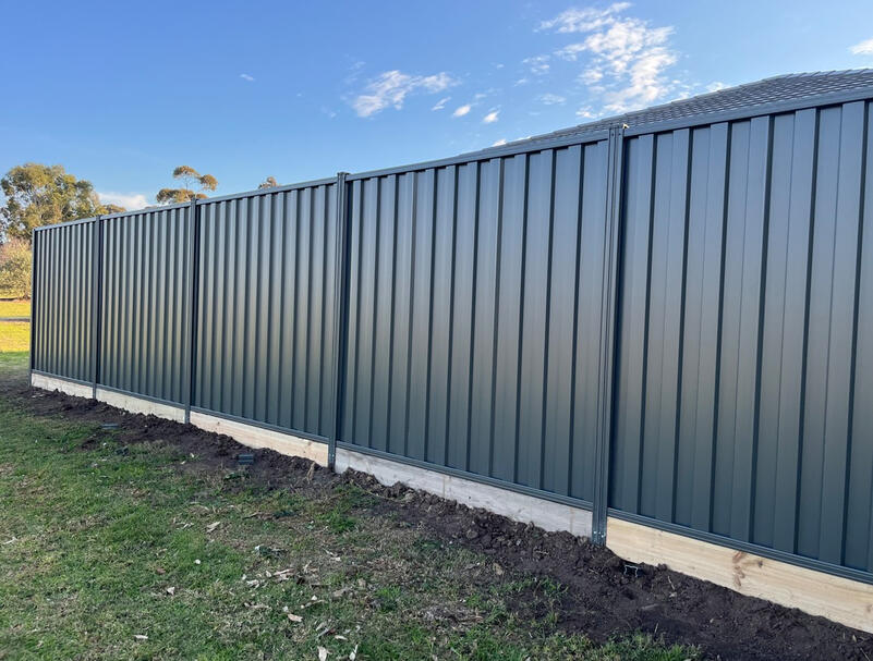 Colorbond Fence Clyde – Monument Colour with Timber Sleepers Colorbond fence in Monument colour with timber sleepers installed in Clyde Melbourne